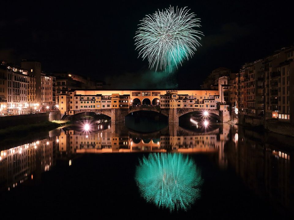 Un fuoco d'artificio verde sopra il Ponte Vecchio, riflesso nell'Arno di notte