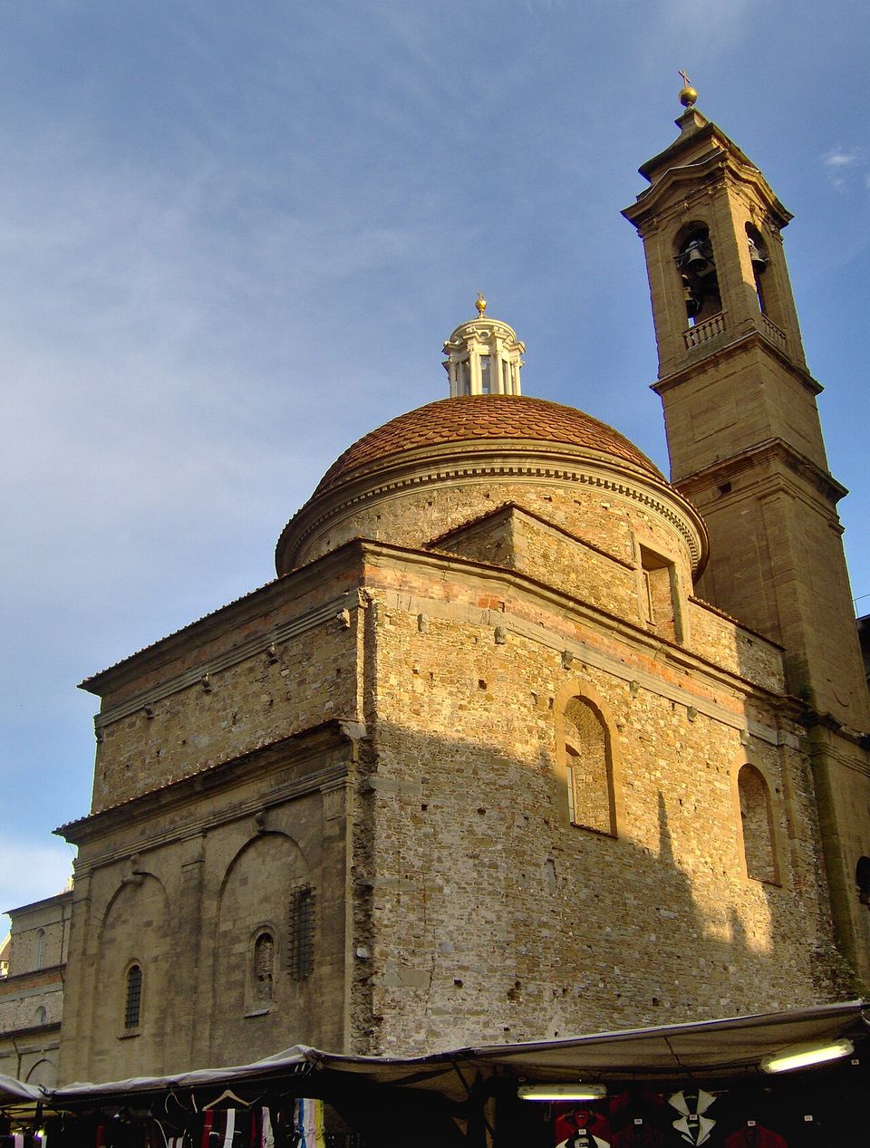 L'esterno della Sagrestia Nuova con la cupola e la lanterna, accanto al campanile di San Lorenzo; sotto, i banchi del mercato