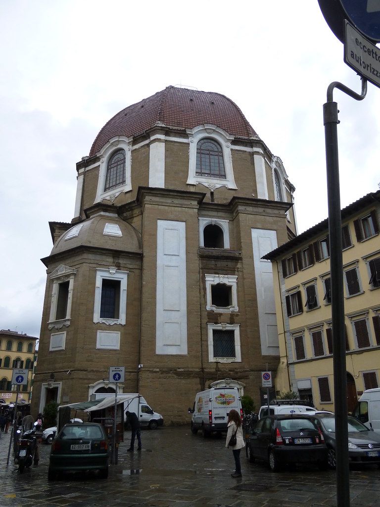 La cupola a tegole rosse delle Cappelle Medicee vista dalla strada, con le auto e i banchi sotto