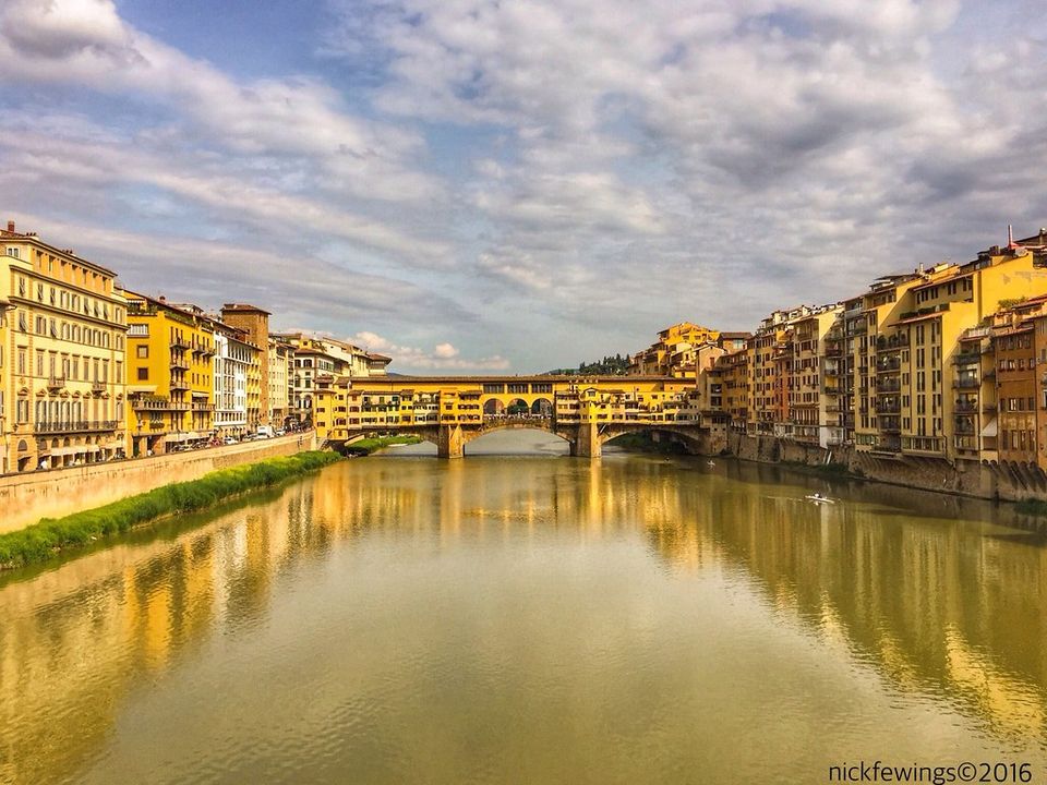 Il Ponte Vecchio in fondo all'Arno, fra i palazzi dei due lungarni, con un canottiere sull'acqua