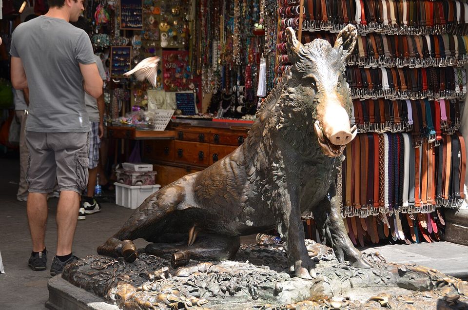 Il Porcellino di bronzo col muso lucido davanti alle bancarelle di cinture del Mercato Nuovo