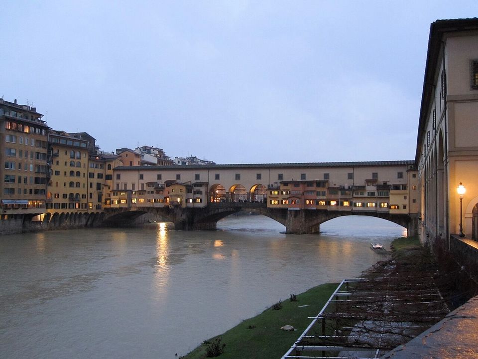 Il Ponte Vecchio di scorcio al crepuscolo, con le luci delle botteghe accese sull'Arno